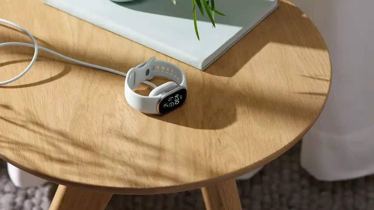 Fitbit Edge cargándose sobre una mesa auxiliar, en una imagen promocional de Google.